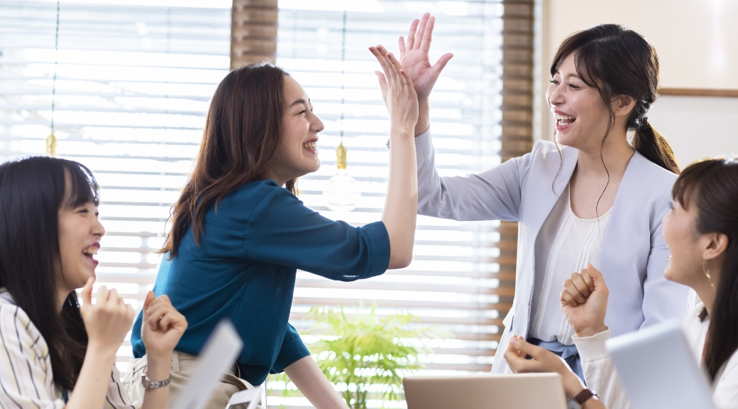 オフィスで笑顔でハイタッチをする女性たち